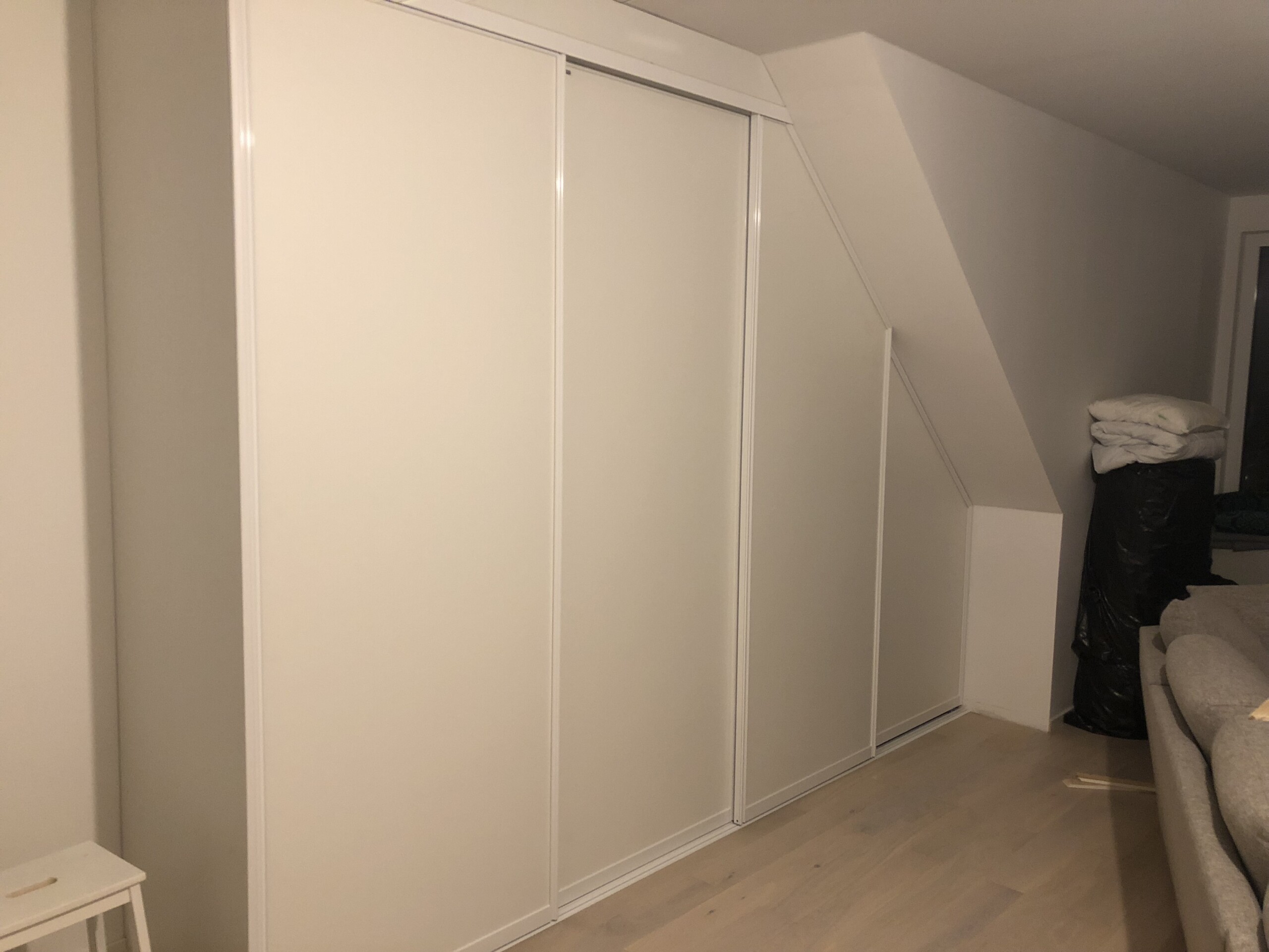 Vita måttanpassade skjutdörrar för snedtak åt sidan från Garderobsfabriken