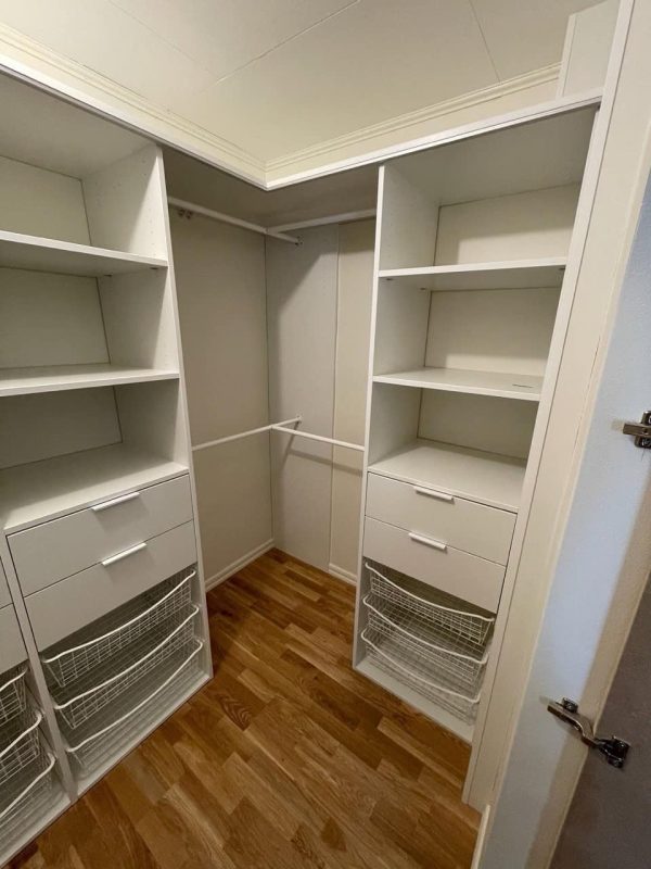Walk in closet / klädkammare med en vit inredning med lådor korgar och klädstång i hörn